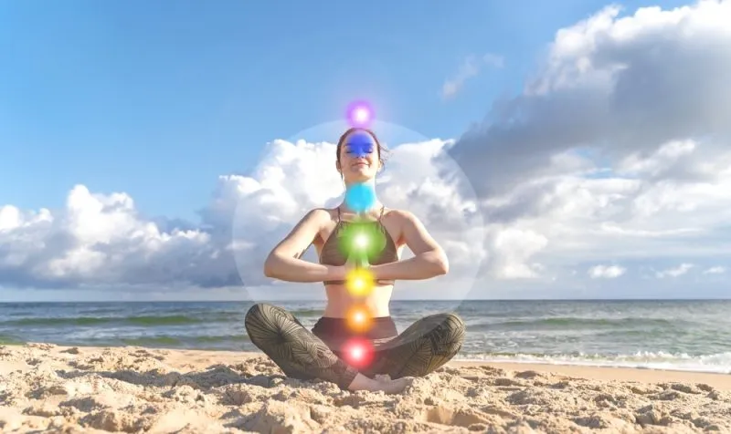 woman-meditating-on-a-beach-with-seven-chakras