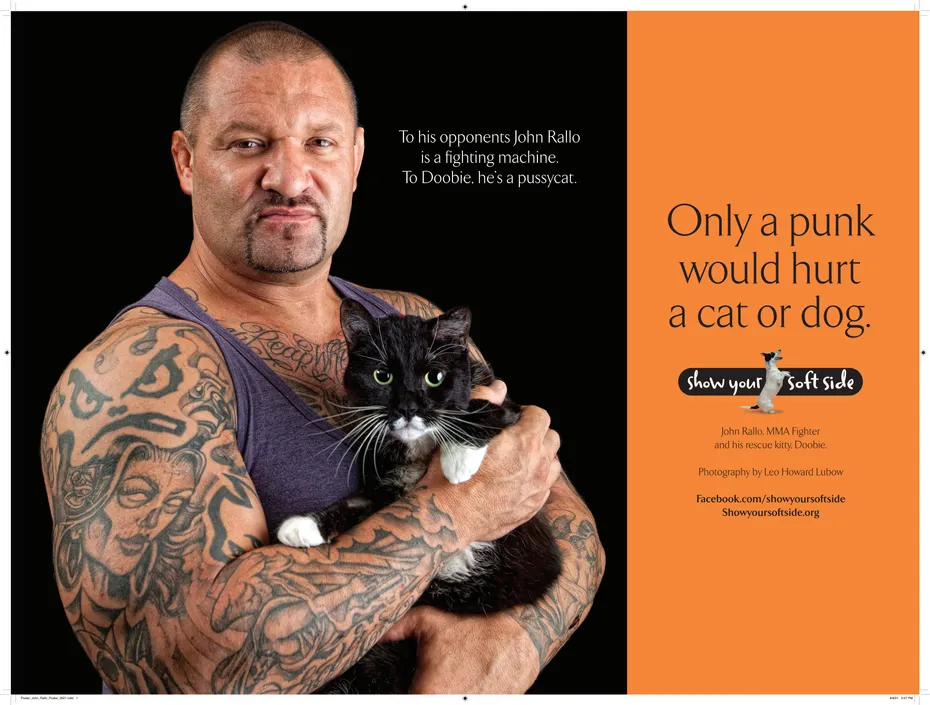 Tattooed man holding a black and white cat for Show Your Soft Side ad