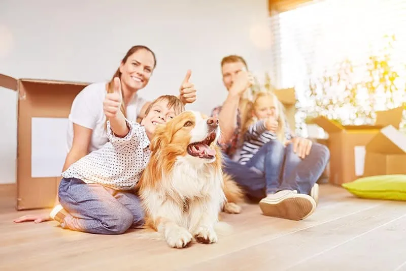 Happy-family-with-two-kids-and-dog-holds-thumbs-up-in-new-home