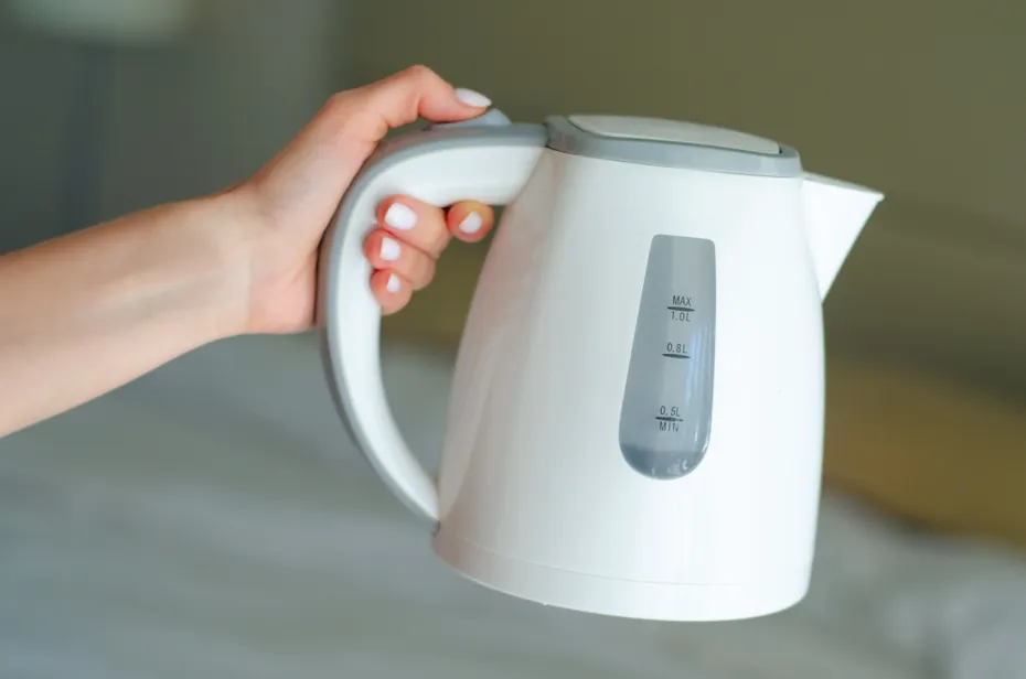 Women hand hold the plastic electric kettle preparing hot water
