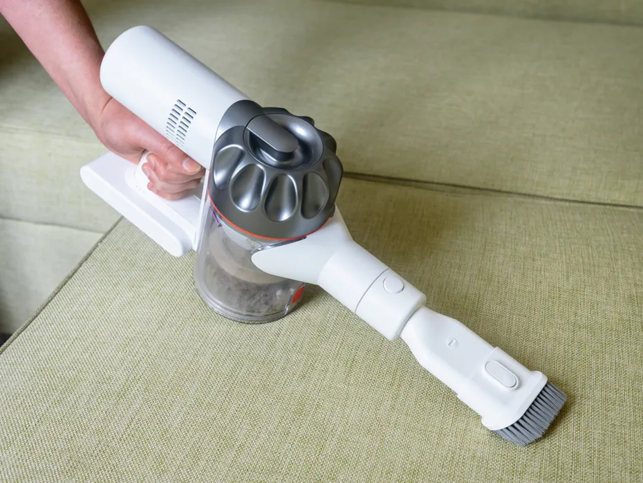 Wireless vacuum cleaner used on sofa in room