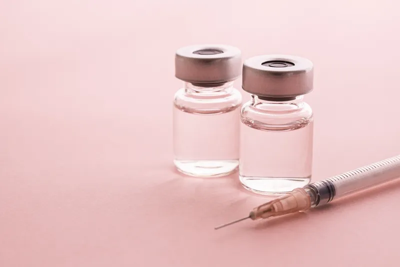 syringe and vial on pink background
