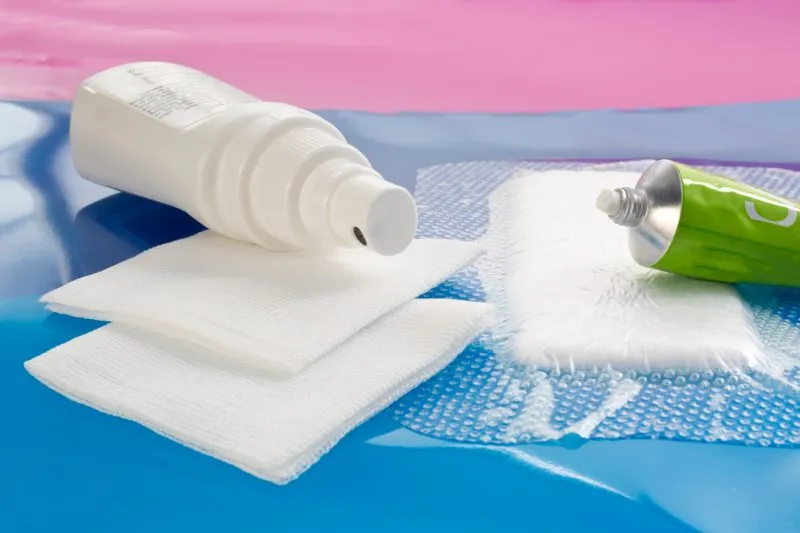 Disinfection solution on two cotton gauze swabs and ointment tube on foam dressing for wounds