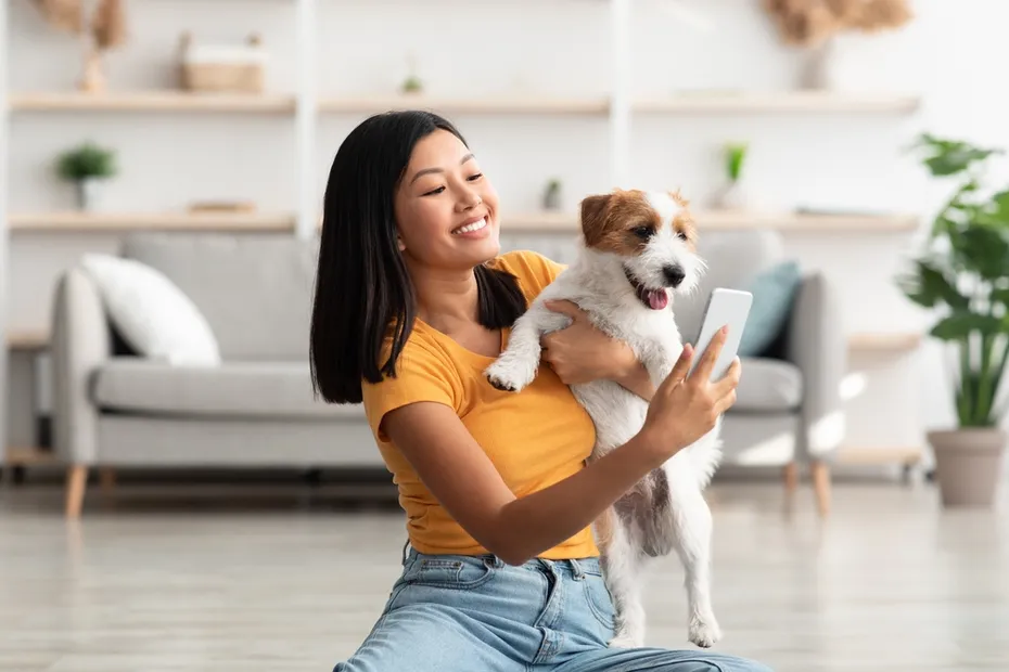 woman sitting on floor taking selfie with her playful cute dog jack russel terrier puppy