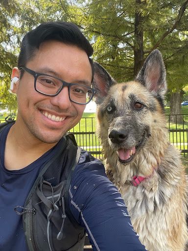Person smiling for a selfie with a dog with heterochromia in a park
