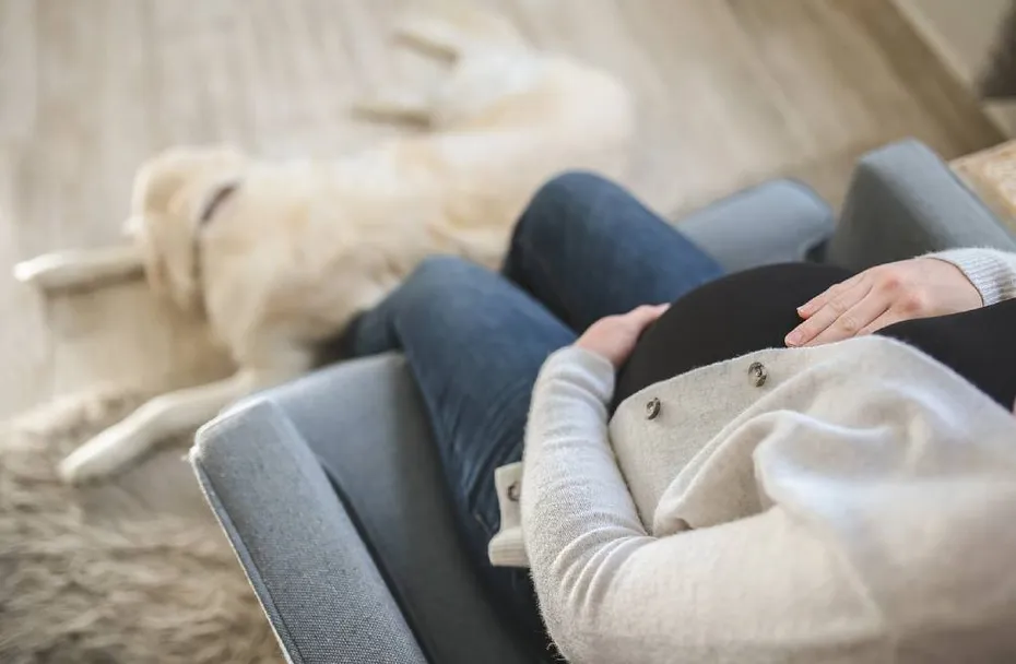 pregnant woman with her pet dog by her feet