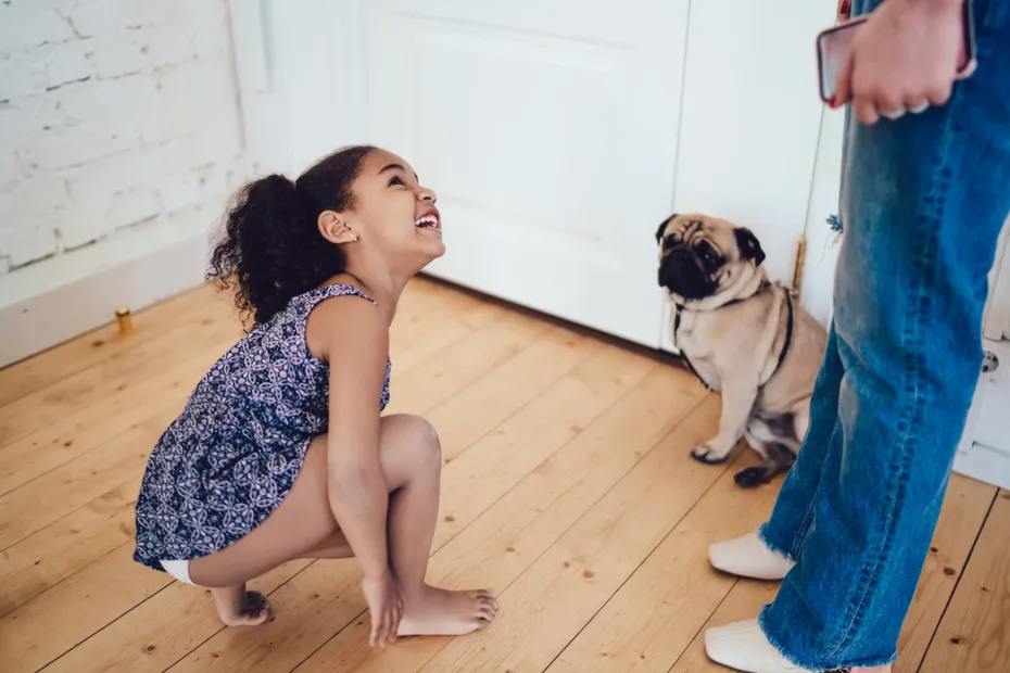 children with a pet pug dog wearing a leash and looking up at the parent