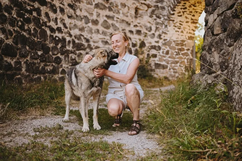 smiling senior woman walking outdoors in ancient fortress hugging homeless big dog