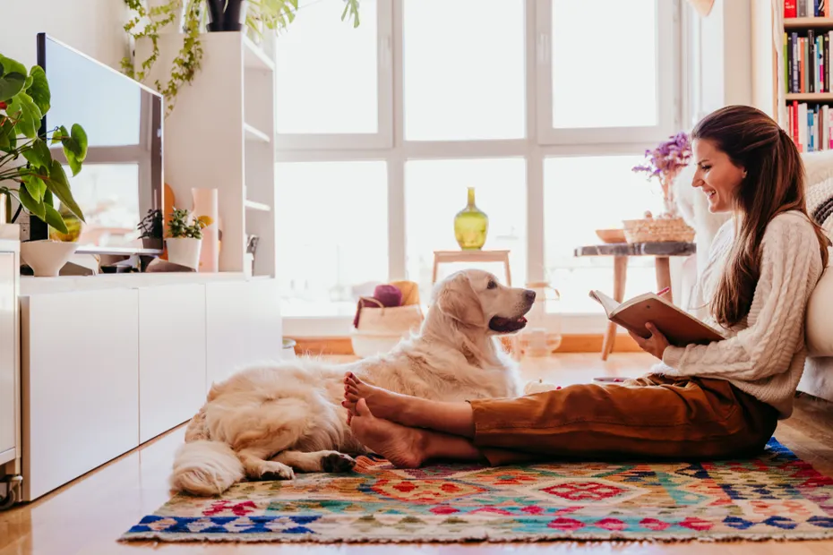 woman sitting on the floor with golden retriever dog while writing