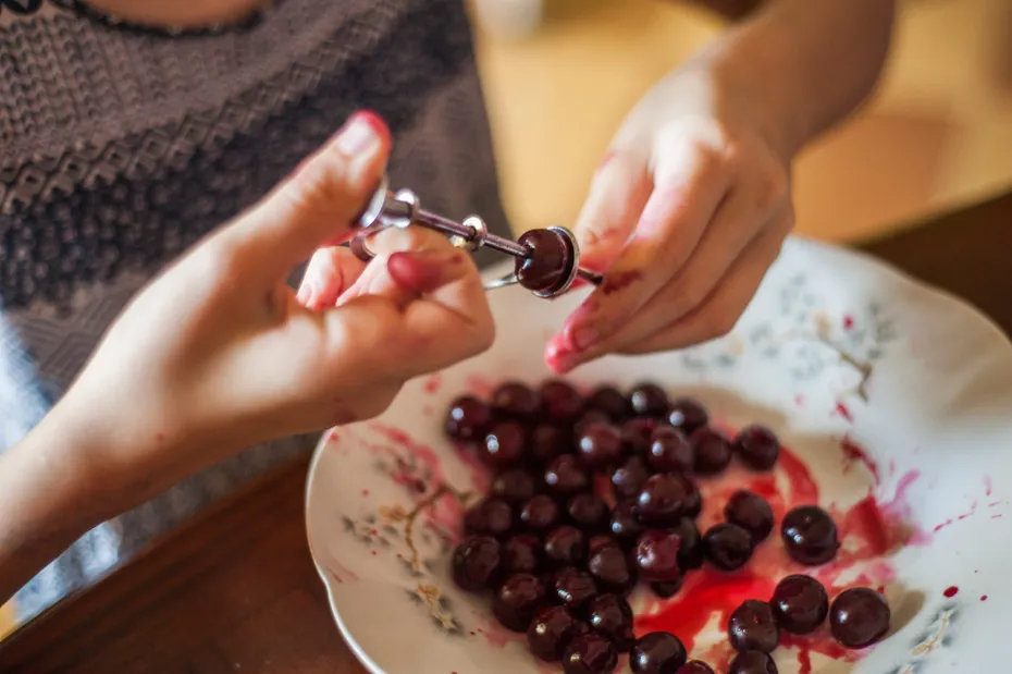 Women's hands remove bones from the cherry with a special device