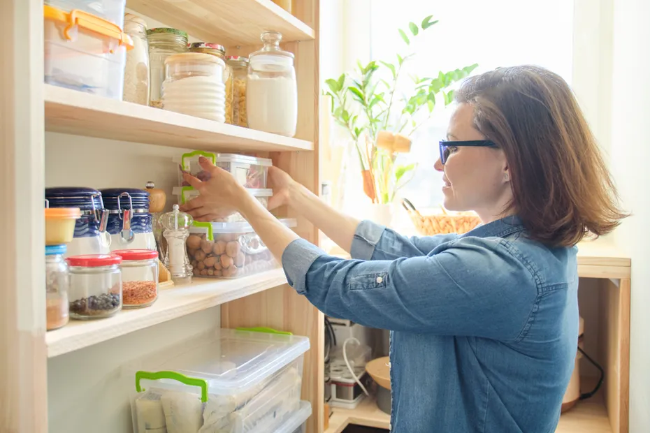 woman-taking-kitchenware-and-food-from-the-shelves