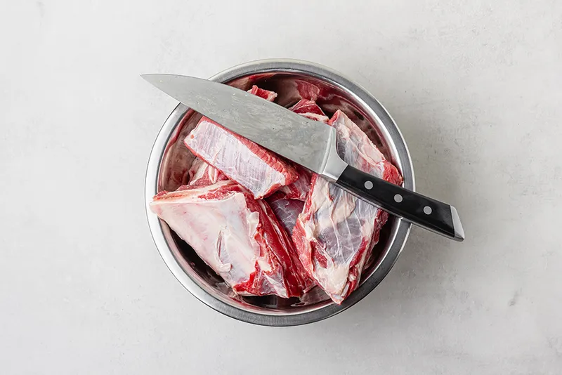 raw beef ribs in a bowl with knife