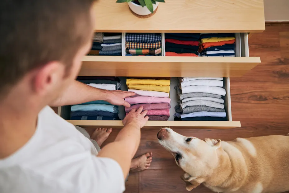 man organizing clothes and dog looking at it