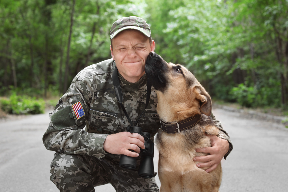 Man in military uniform with German shepherd outdoors
