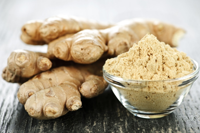 Fresh and ground ginger on wooden table