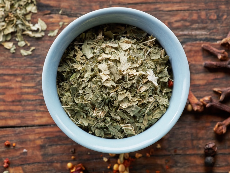 bowl of dried oregano on wooden table
