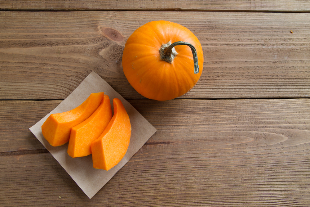 pumpkin slices on parchment paper and the whole pumpkin