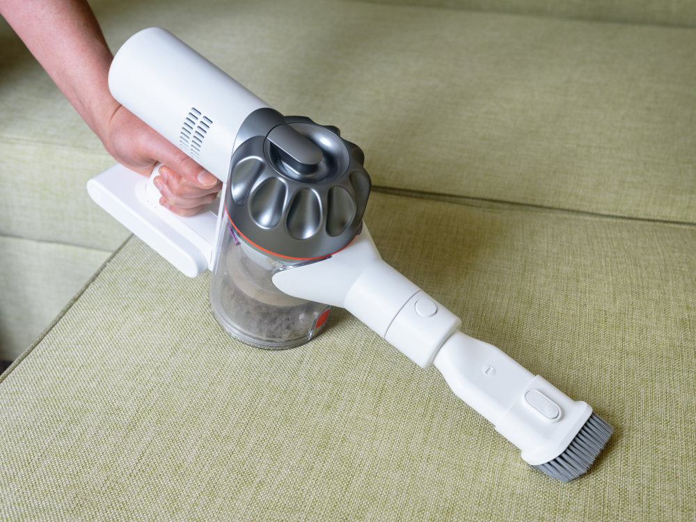 Wireless vacuum cleaner used on sofa in room