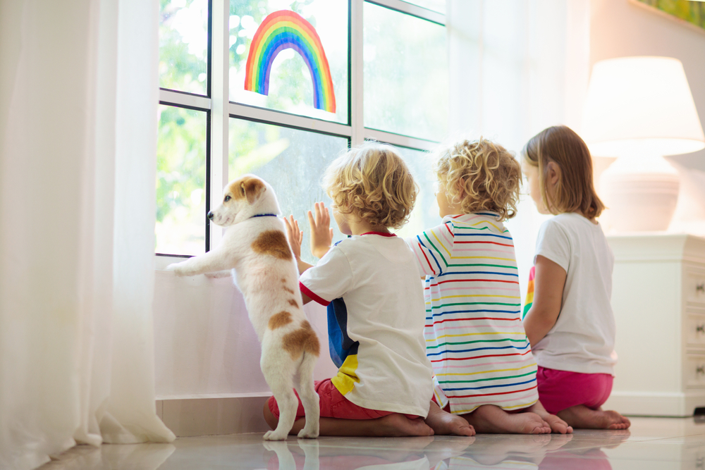 children with their pet dog kneeling by the window
