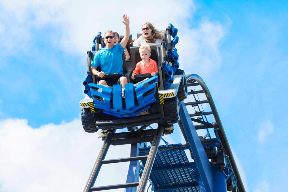 Young family having fun riding a rollercoaster at a theme park